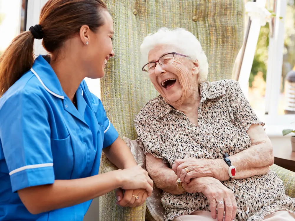 Happy nurse smiling and laughing with elderly lady